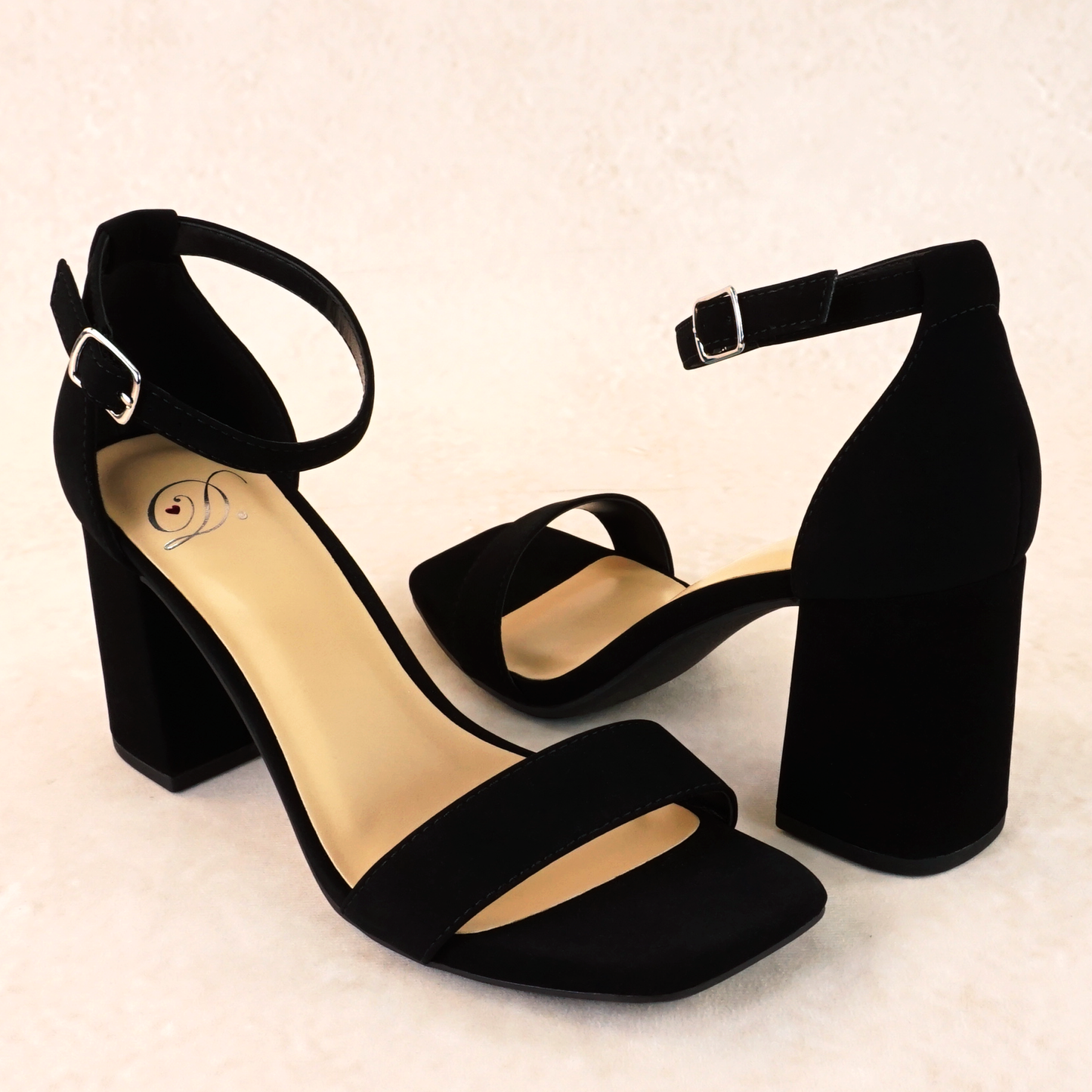 A black block heel in a soft nubuck material with an adjustable ankle strap and single strap across the toes
