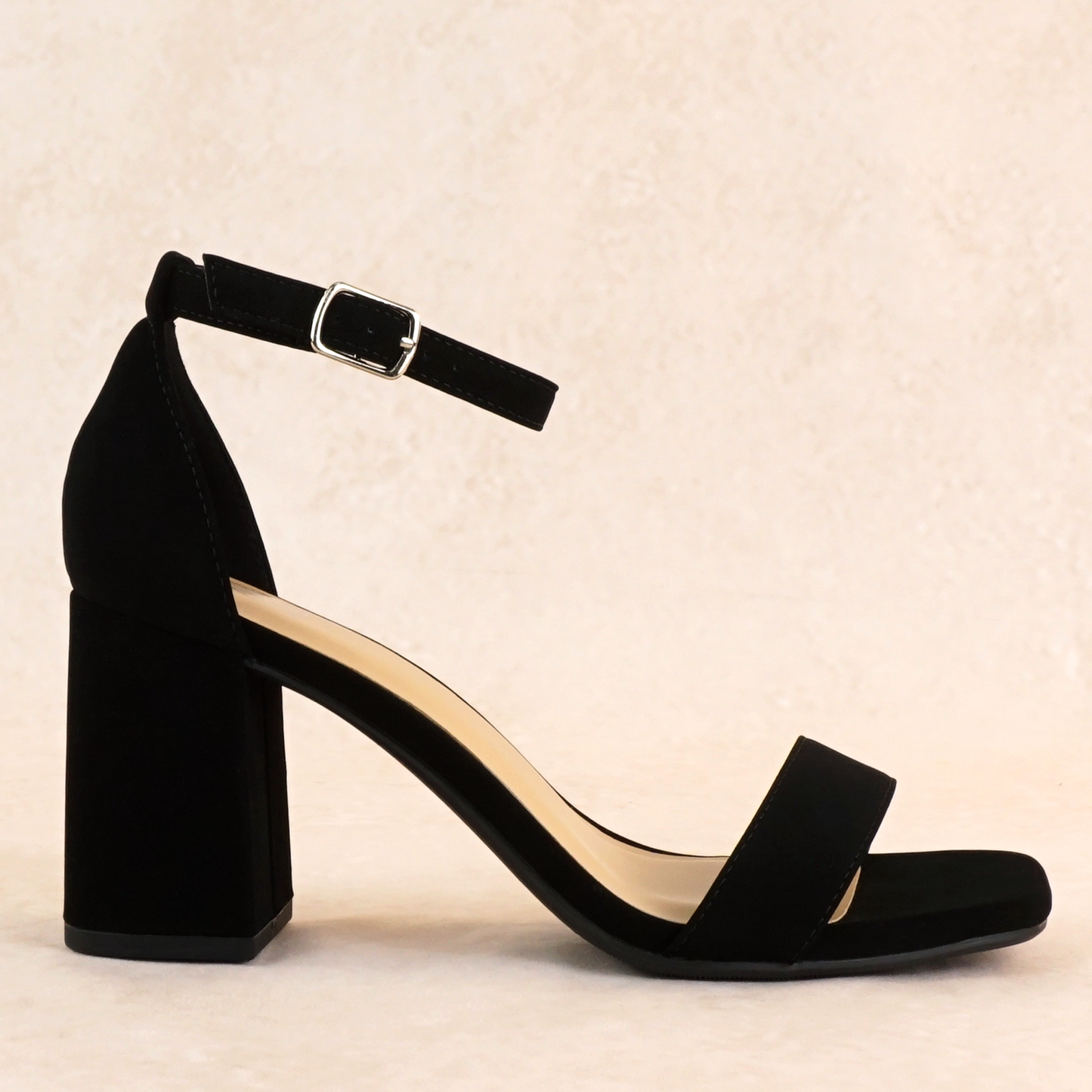A black block heel in a soft nubuck material with an adjustable ankle strap and single strap across the toes