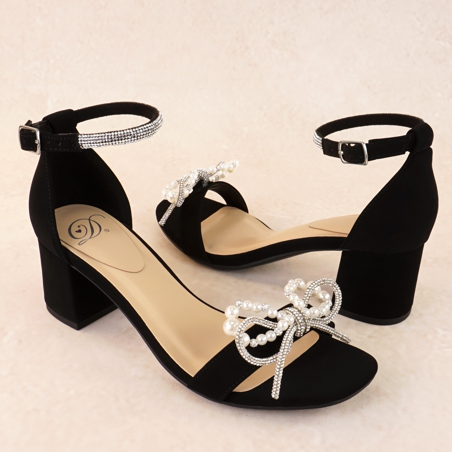A black nubuck block heel with a pearl and rhinestone bow on a single strap across the toes and a rhinestone adjustable ankle strap