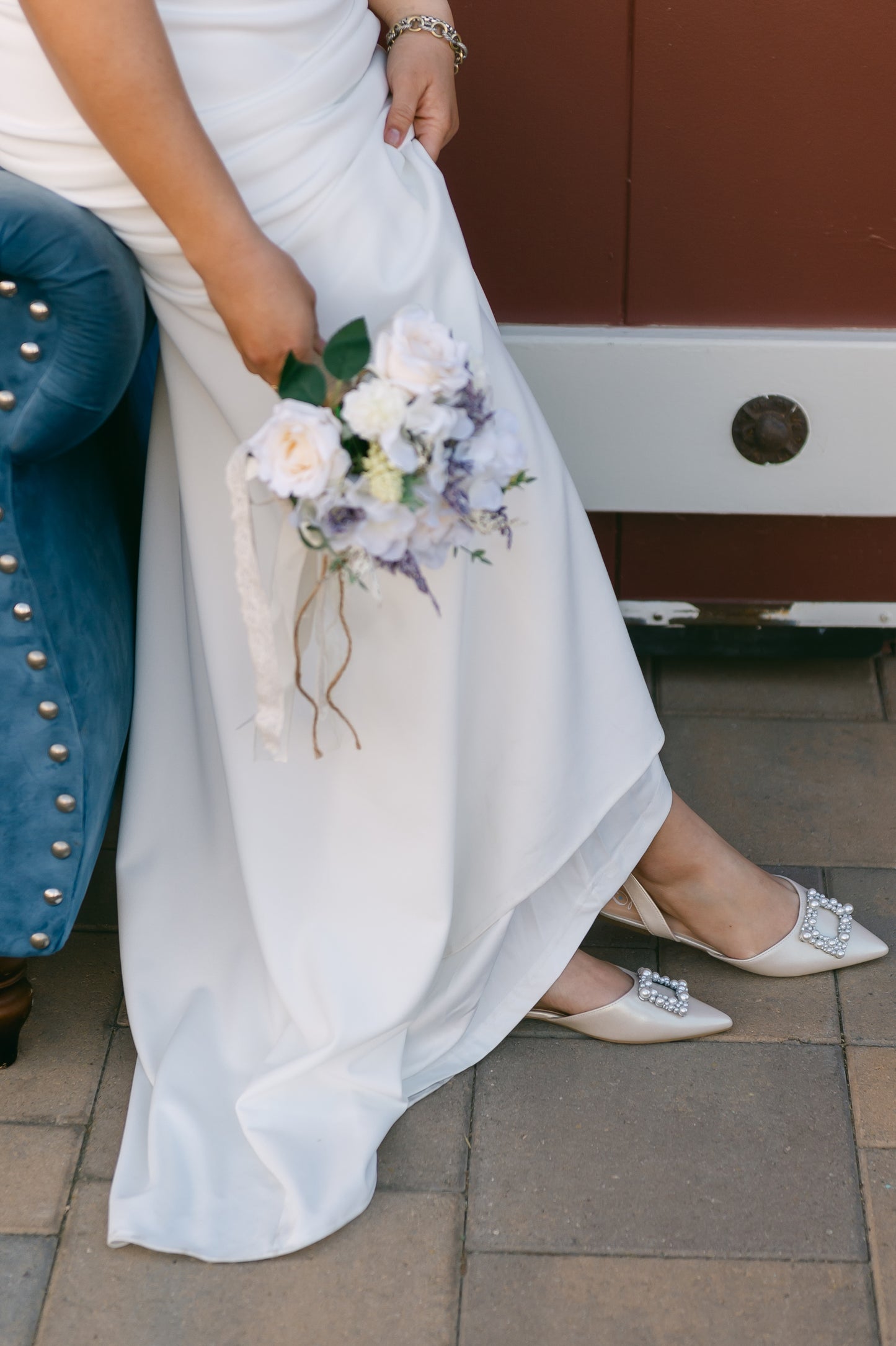 Slingback flat with a pearl buckle accent in a pearl shimmer worn by a woman in a white dress