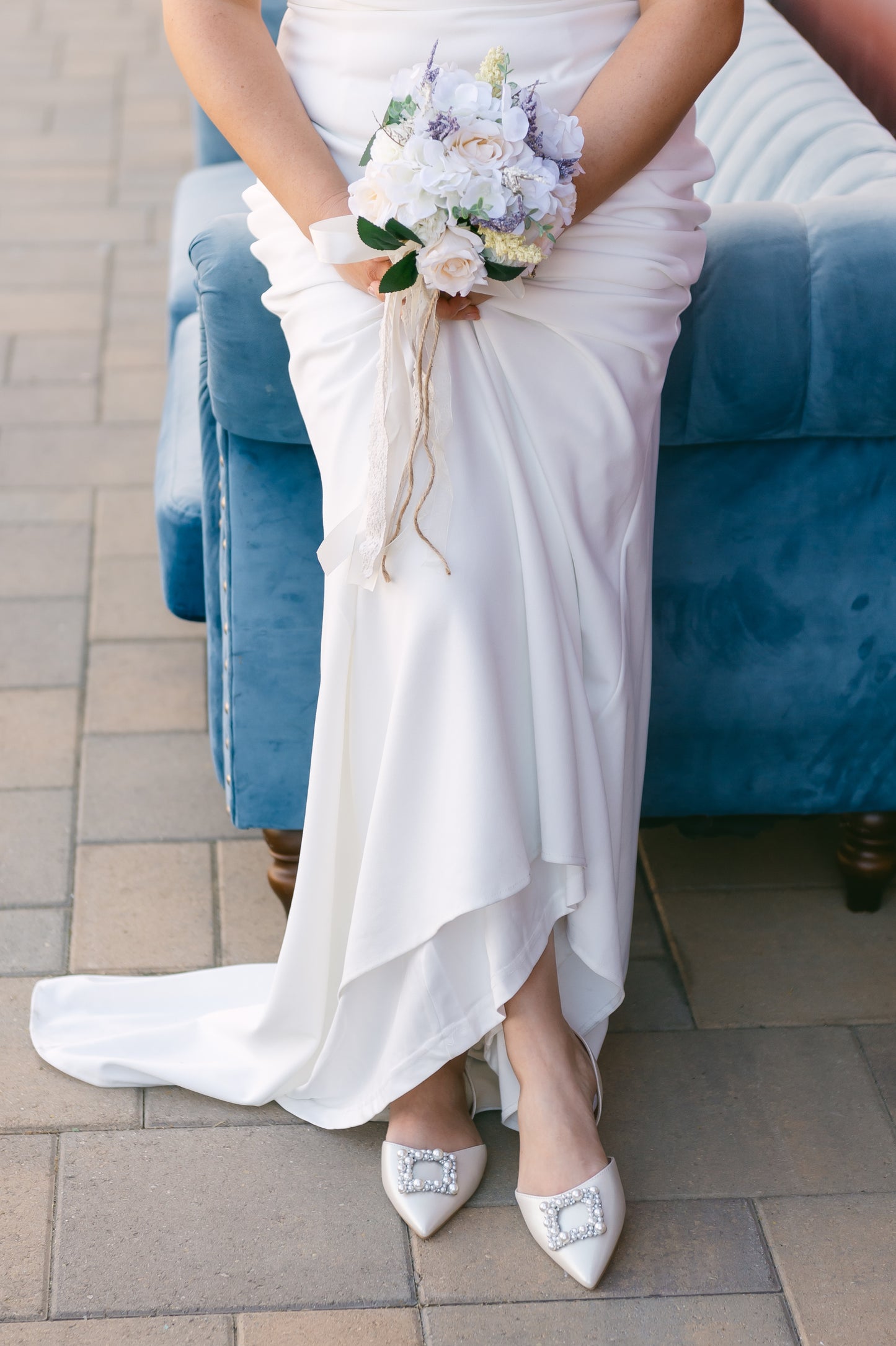 Slingback flat with a pearl buckle accent in a pearl shimmer worn by a woman in a white dress
