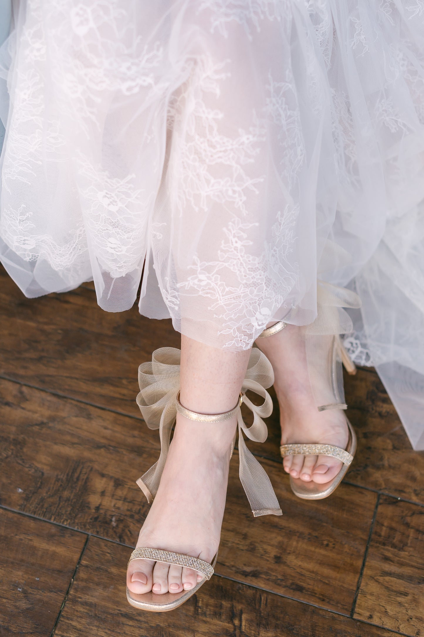 4" stiletto heel in gold with rhinestone band and wire mesh statement bow worn by a woman in a white dress