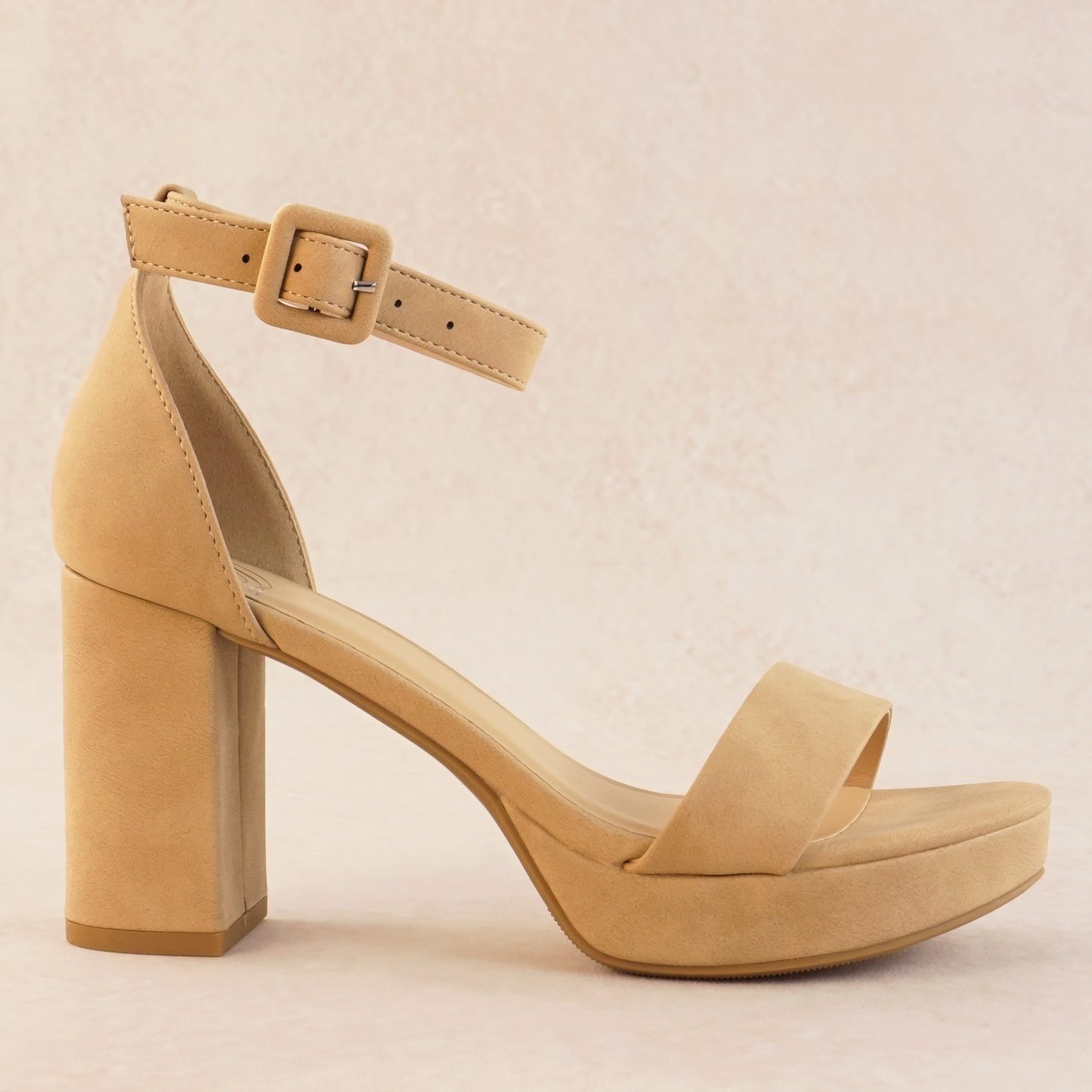 An open-toe block heel platform shoe in a natural tan color in soft nubuck material with a thick buckle on an adjustable ankle strap and single band across the toes