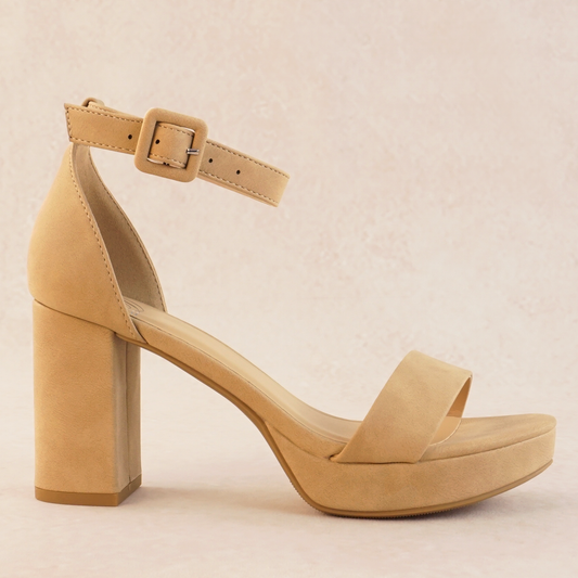 An open-toe block heel platform shoe in a natural tan color in soft nubuck material with a thick buckle on an adjustable ankle strap and single band across the toes