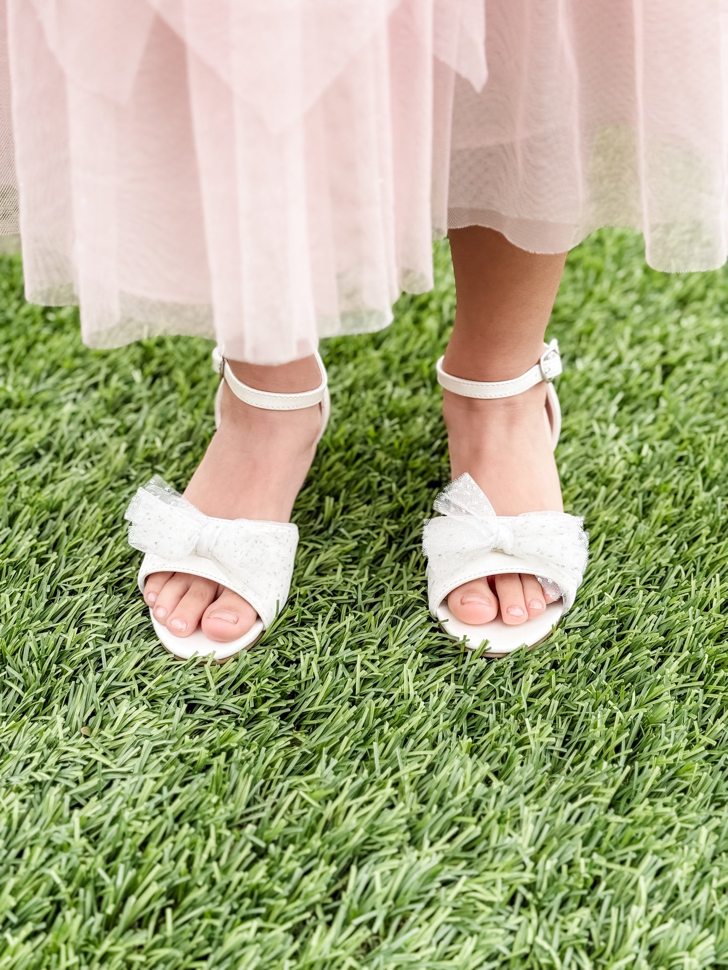 1.75" block heel white sandal with tulle glitter bow detail being worn