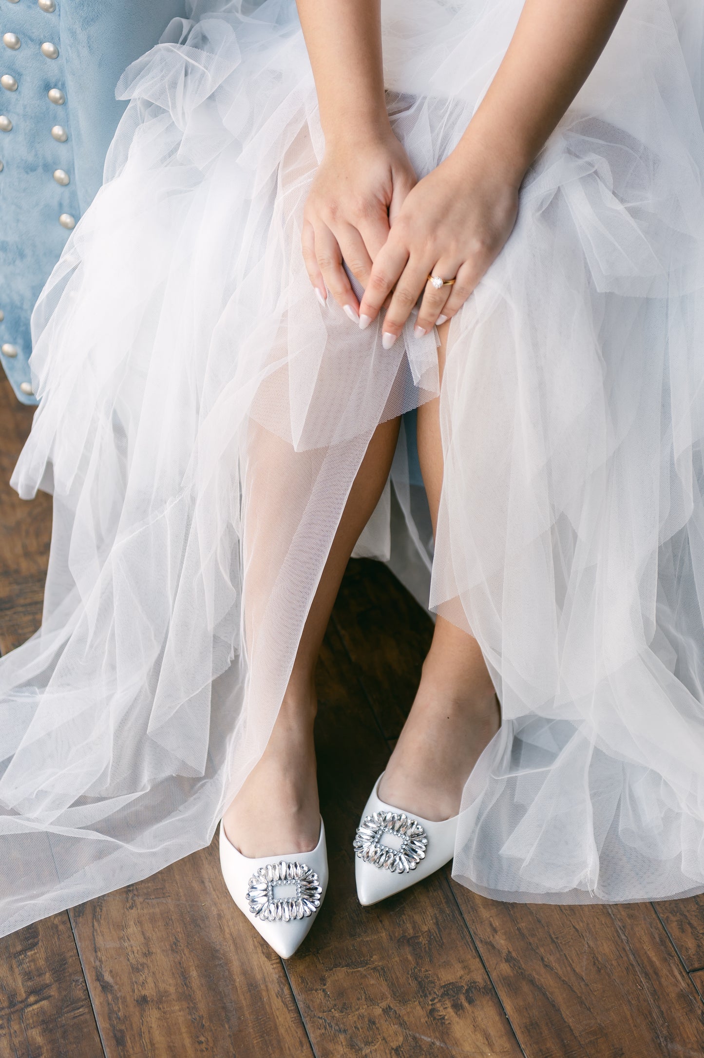 White pointed-toe slingback flat shoe with rhinestone accent worn by woman in white dress