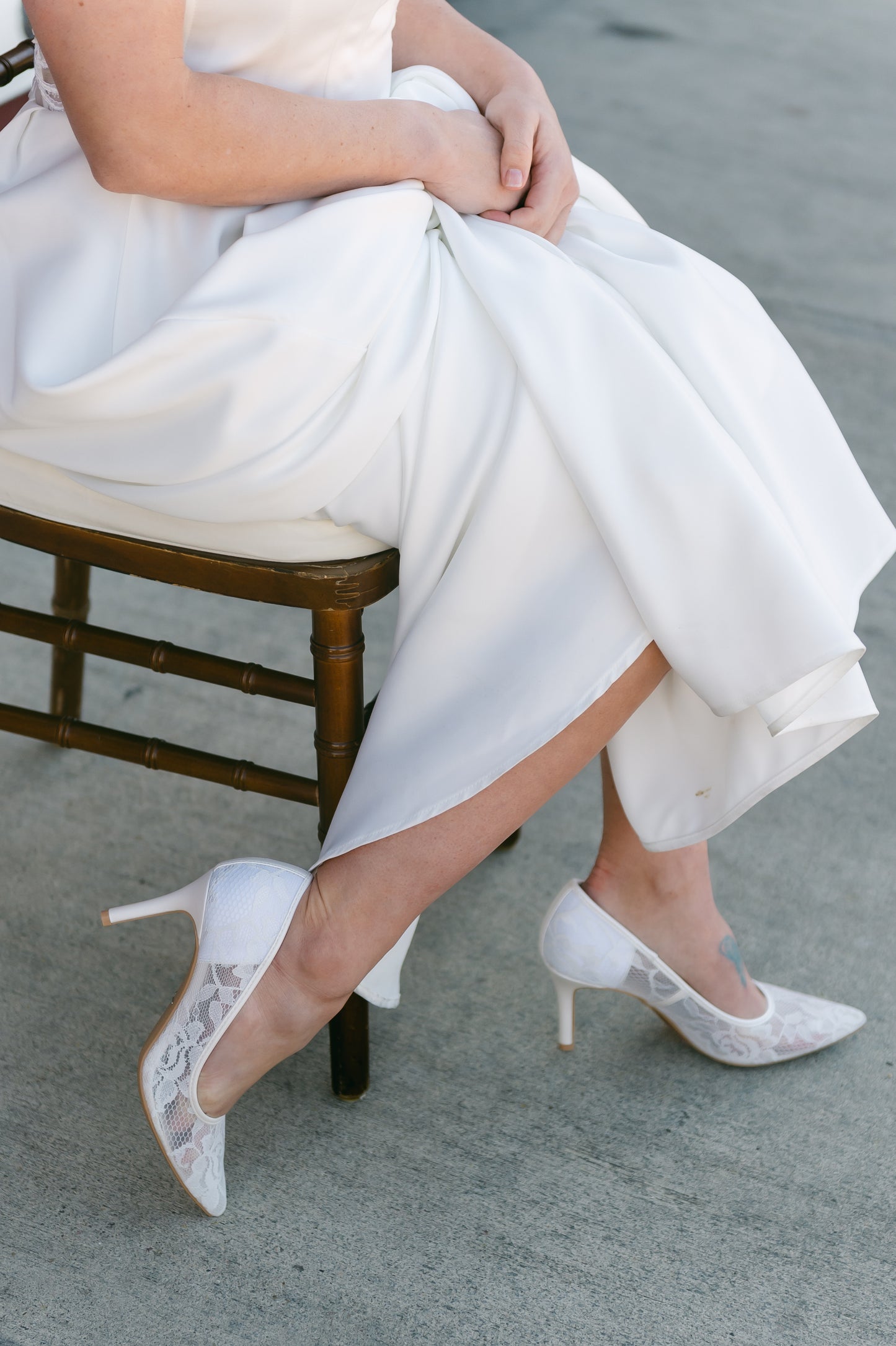 Classic white allover sheer lace stiletto pump with a 3.5" heel worn by a woman in a white dress