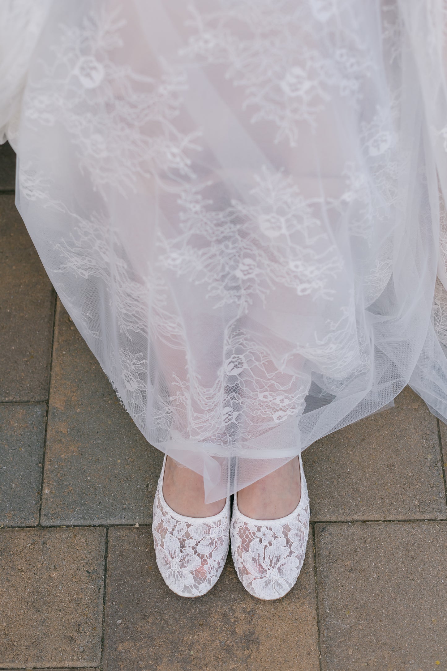 Allover lace white ballet flat with elasticized Mary Jane strap worn by a woman in a white dress