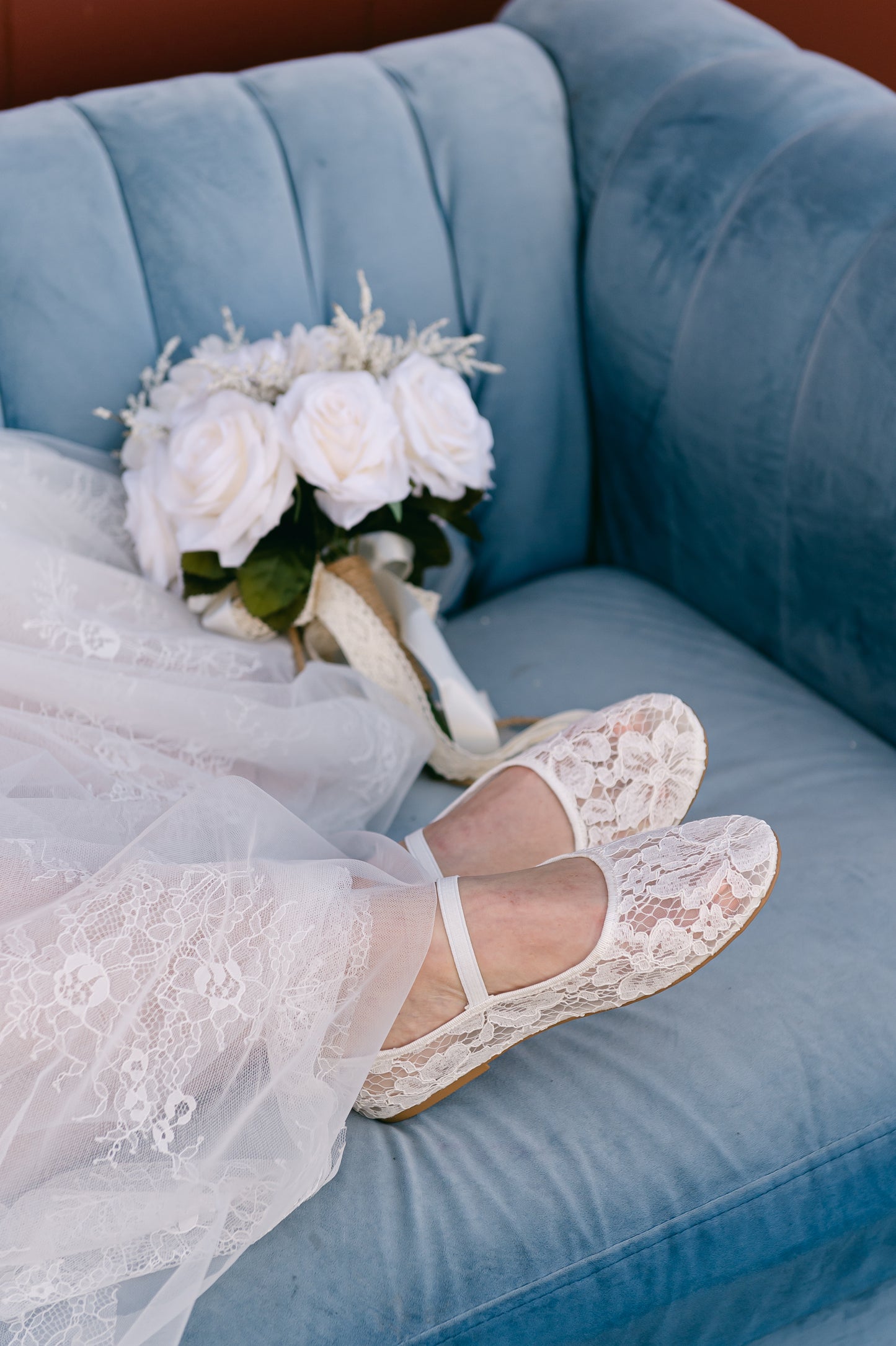 Allover lace white ballet flat with elasticized Mary Jane strap worn by a woman in a white dress