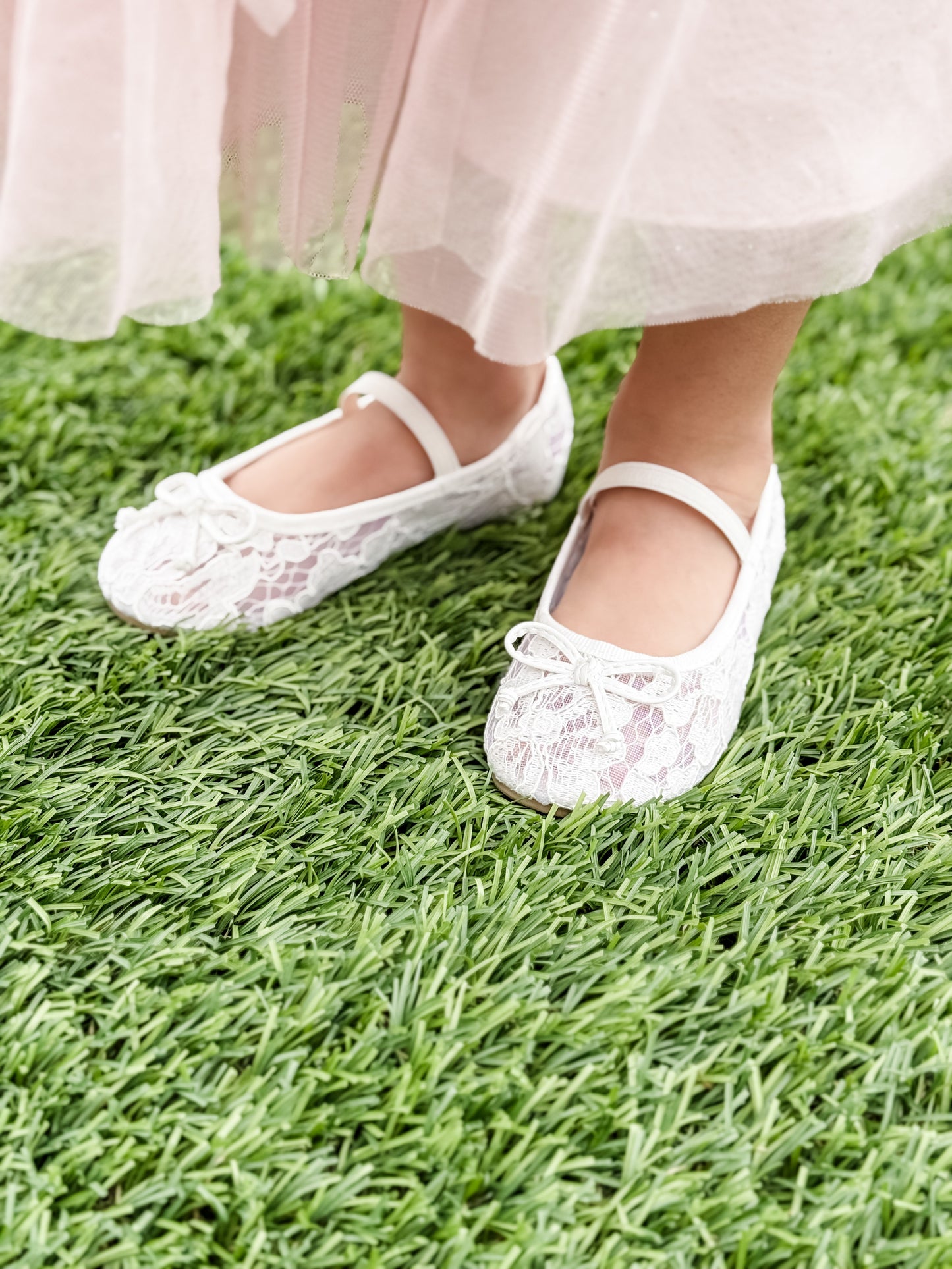 Allover lace flat with elasticized Mary Jane strap and bow detail being worn