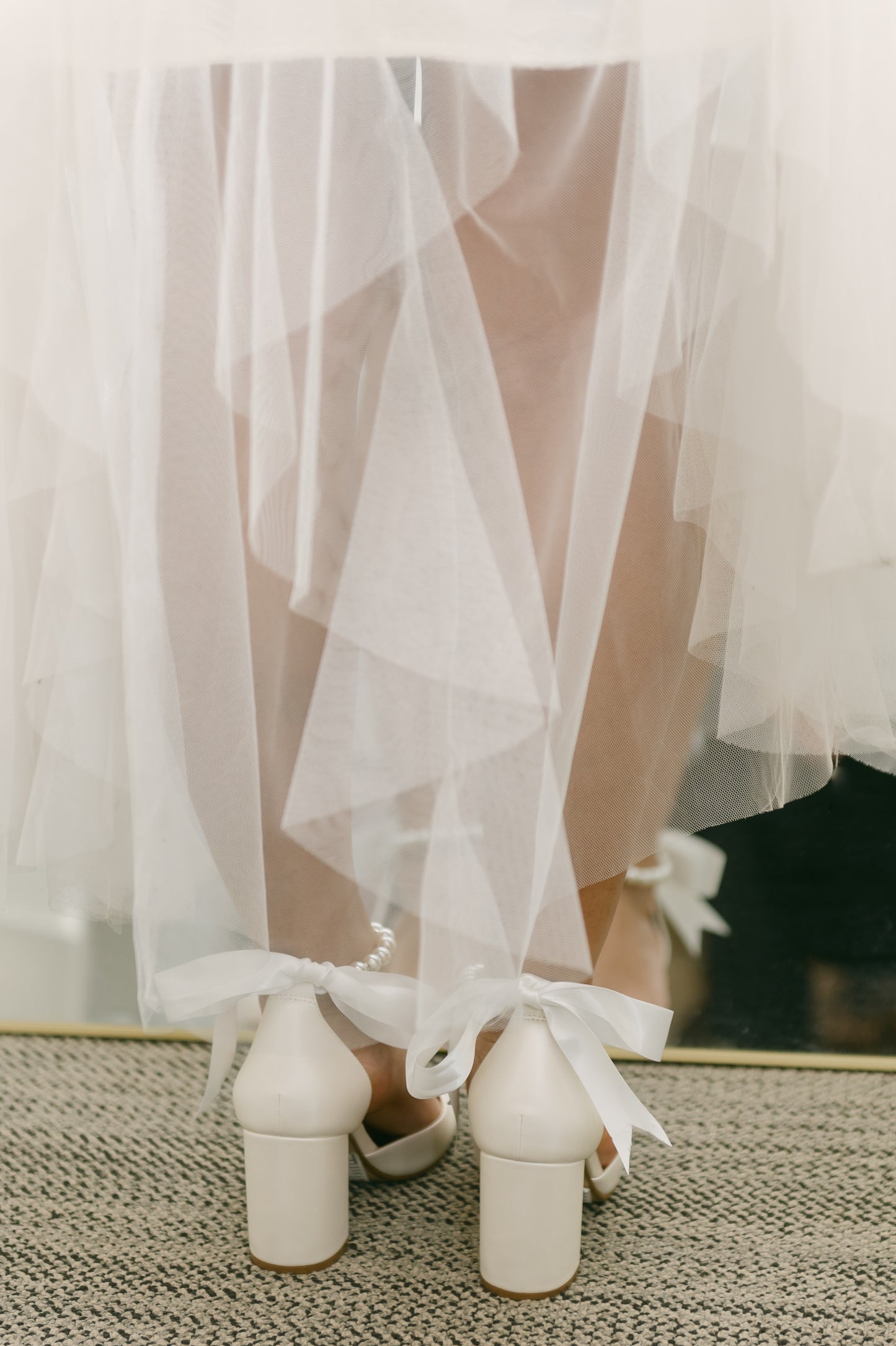 White d'orsay heel with adjustable pearl ribbon ankle tie and a 3.25" block heel worn by a woman in a white dress