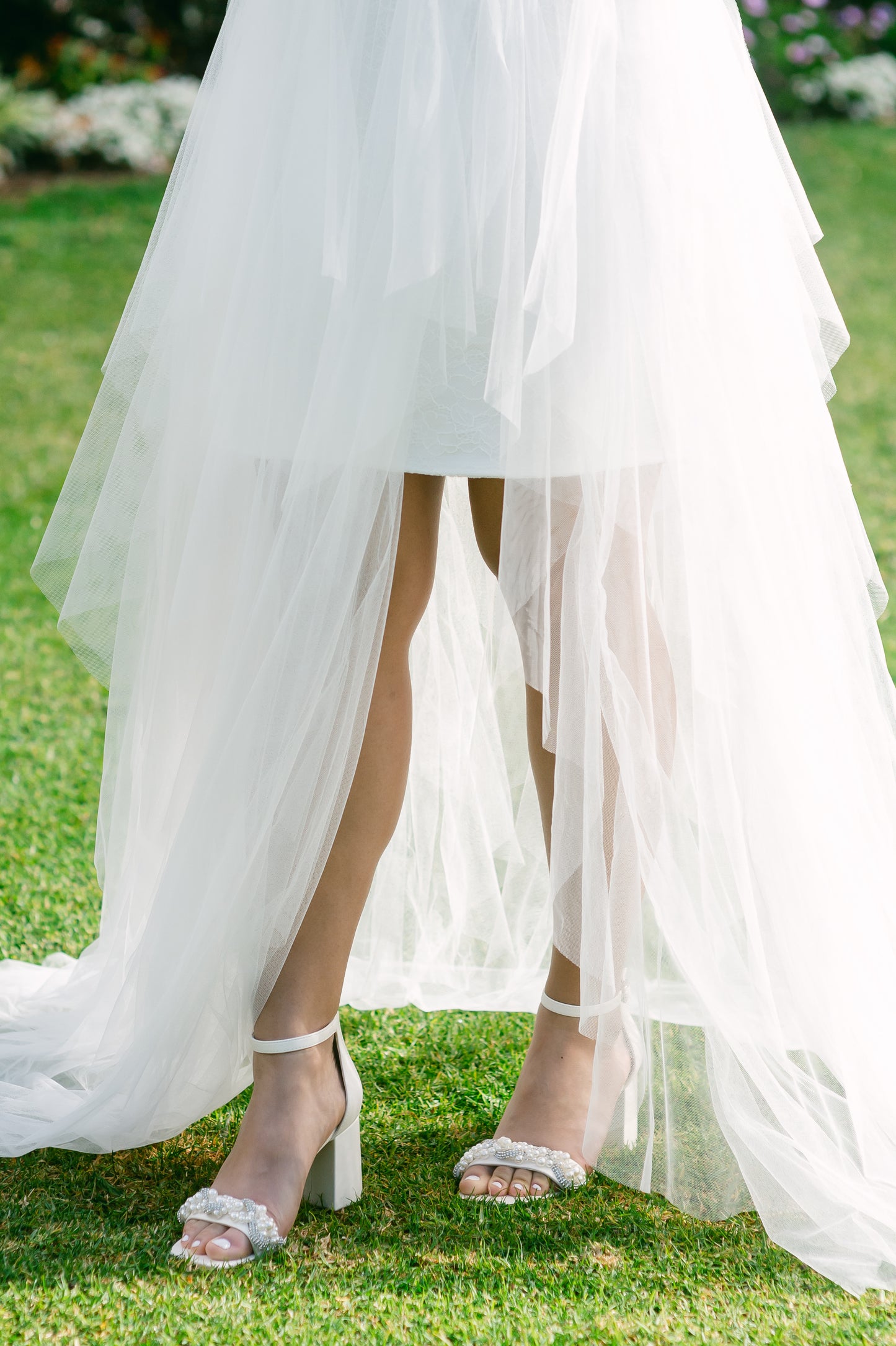 Pearls and rhinestones intertwined on a wide fit single-band 3.25" ankle strap block heel worn by a woman in a white dress