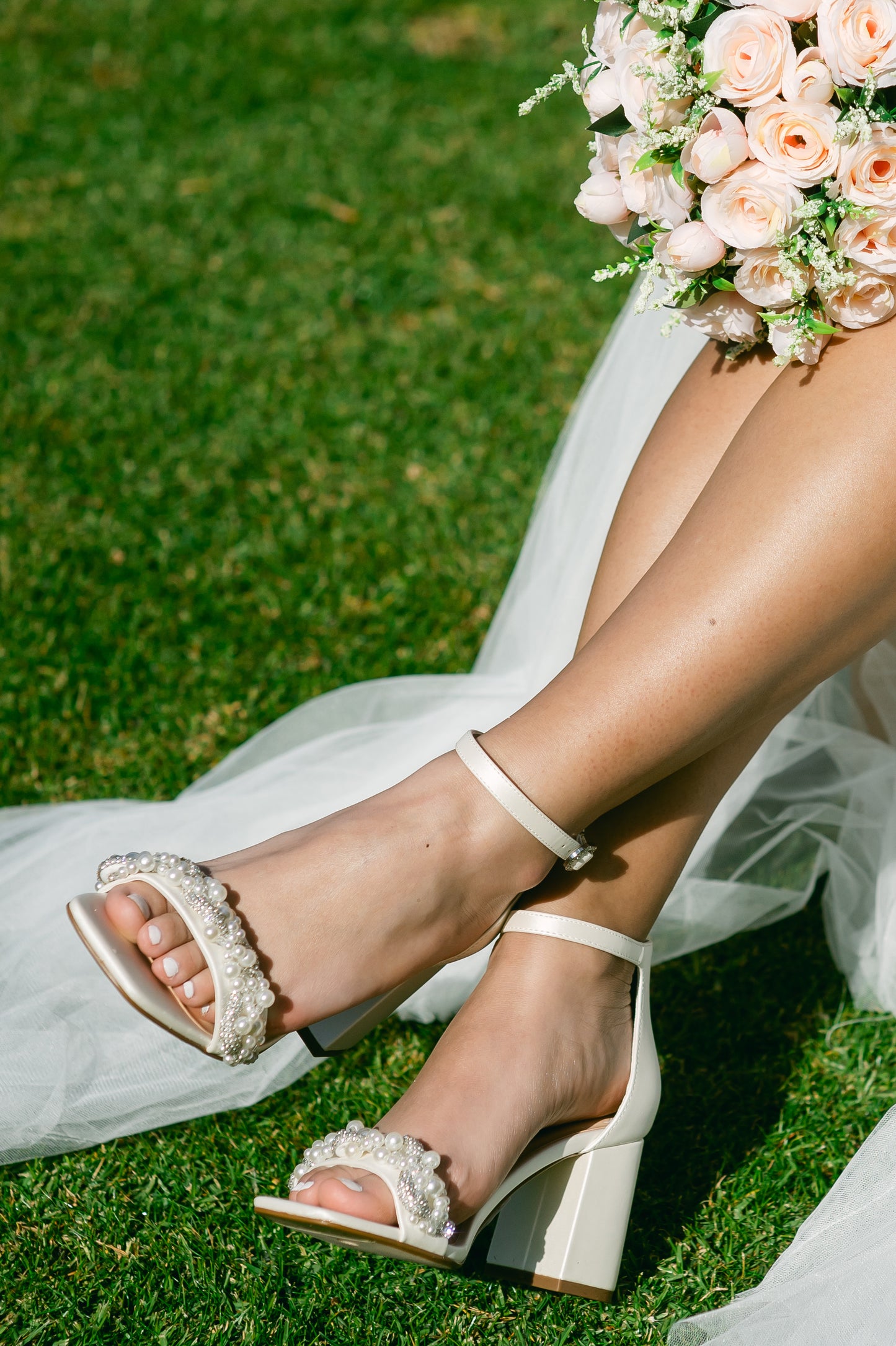 Pearls and rhinestones intertwined on a wide fit single-band 3.25" ankle strap block heel worn by a woman in a white dress