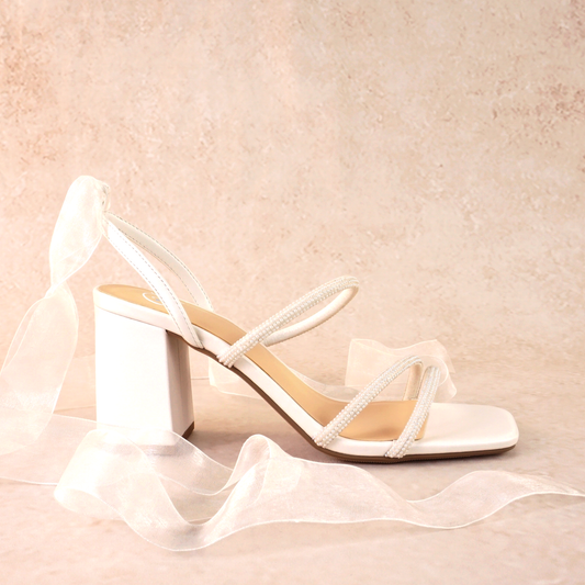 A white open-toe block heel with pearl straps and a ribbon tie
