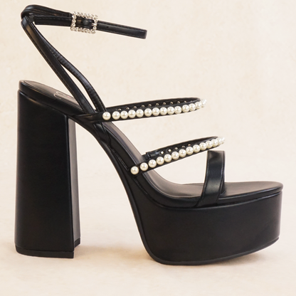 A black platform heel with adjustable ankle strap, rhinestone buckle and pearl straps