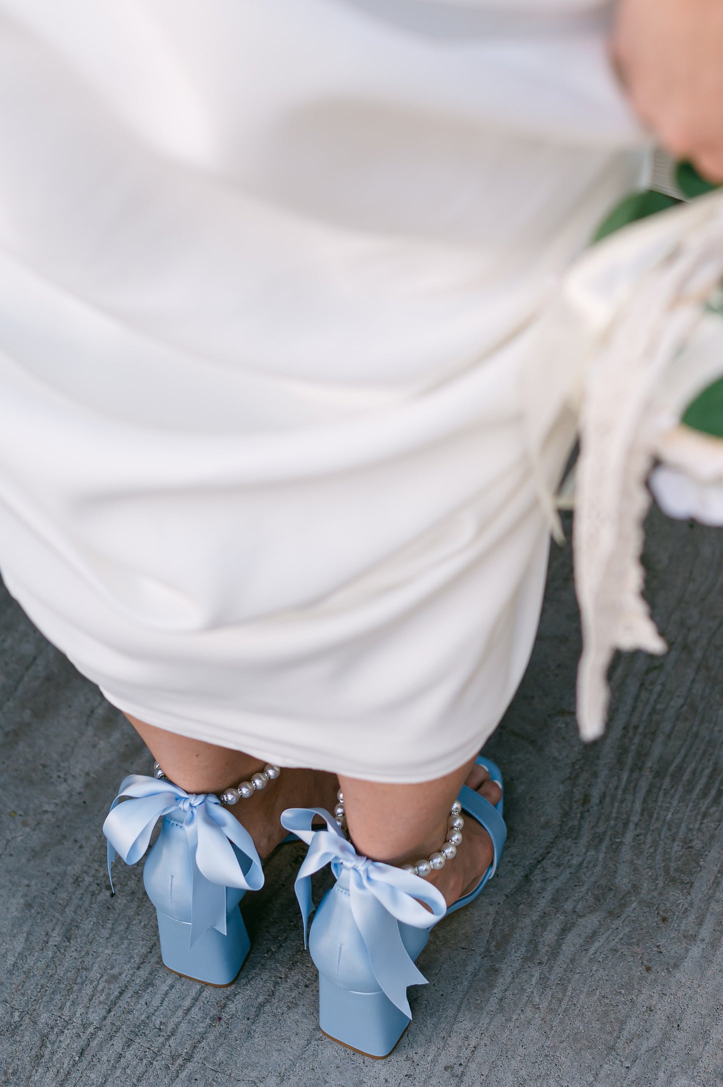 3" flared block heel in blue with adjustable pearl ankle strap and satin ribbon tie worn by a woman in a white dress