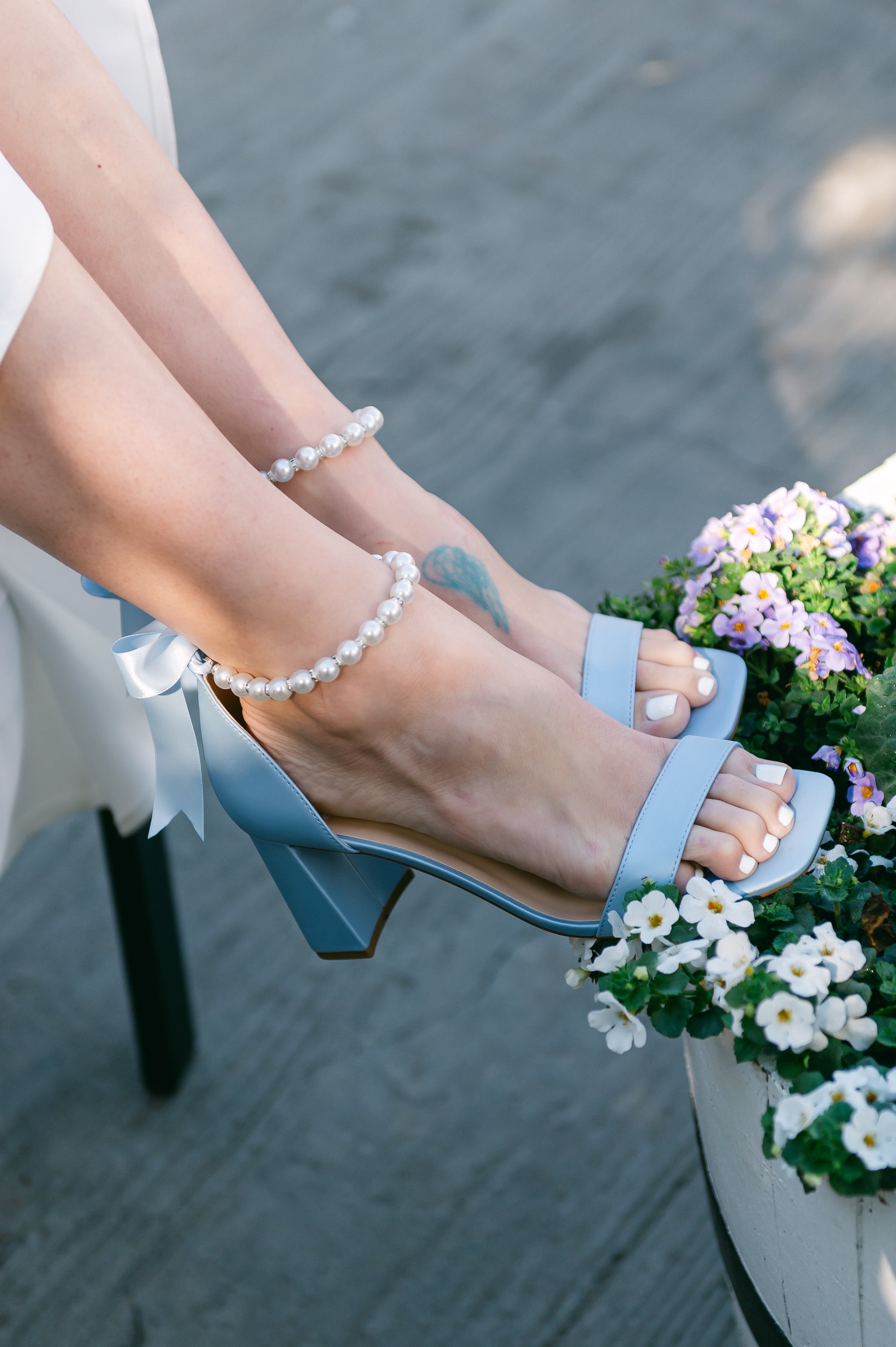3" flared block heel in blue with adjustable pearl ankle strap and satin ribbon tie worn by a woman in a white dress