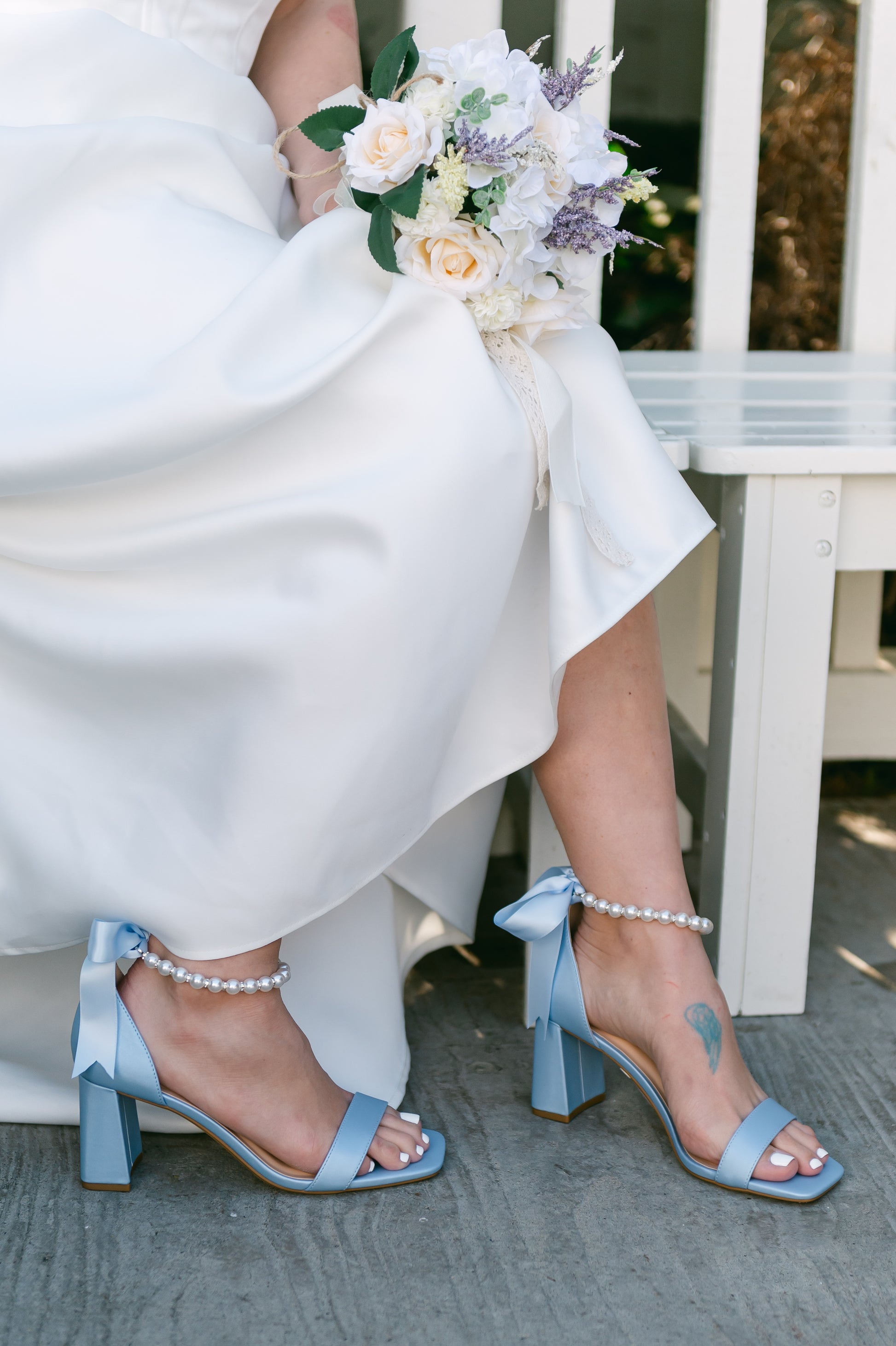 3" flared block heel in blue with adjustable pearl ankle strap and satin ribbon tie worn by a woman in a white dress