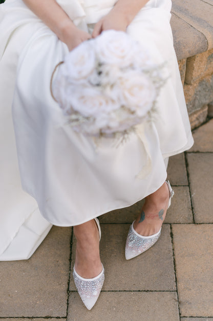 White d’orsay pump with adjustable slingback and a 3.5" heel worn by a woman in a white dress