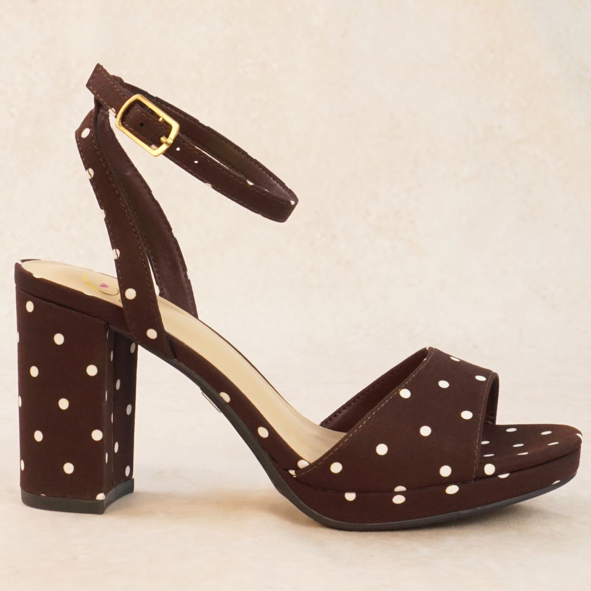 A brown polka dot print heeled sandal with adjustable ankle strap and buckle