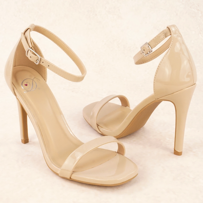 A pair of dark beige patent material stiletto heels with adjustable ankle straps