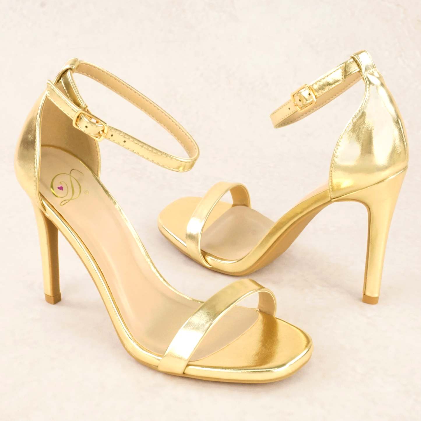 A pair of gold metallic stiletto heels with adjustable ankle strap