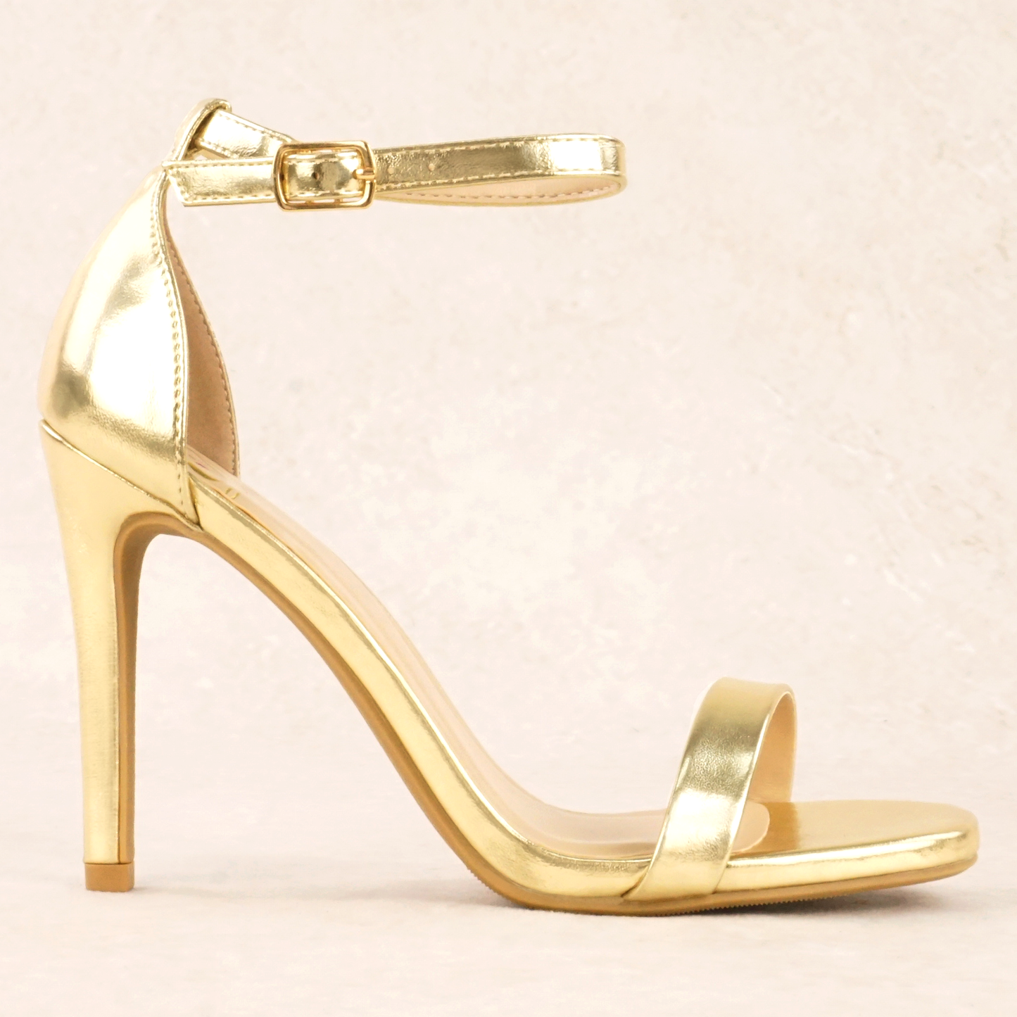 A gold metallic stiletto heel with adjustable ankle strap