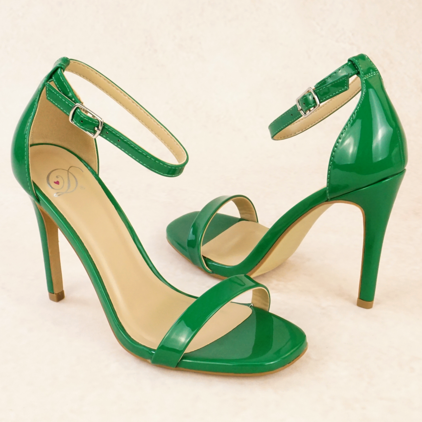 A pair of green patent stiletto heels with adjustable ankle strap