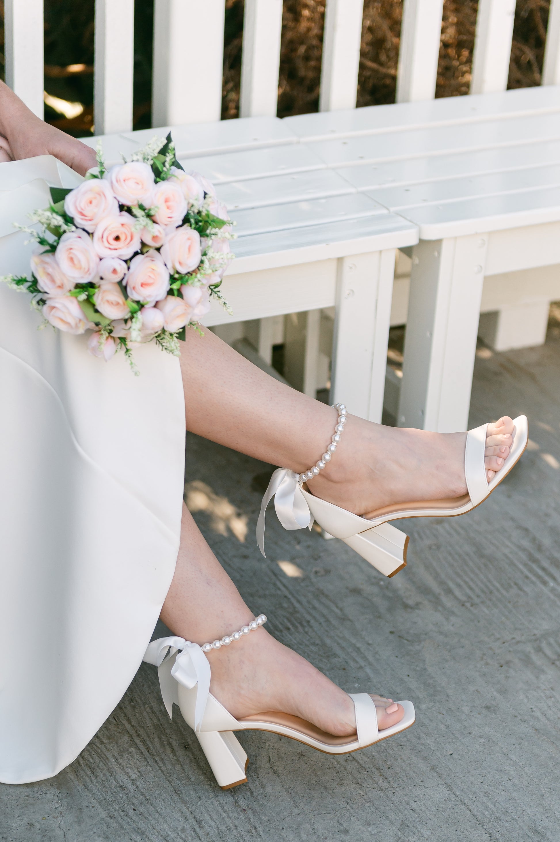 3" flared block heel in white with adjustable pearl ankle strap and satin ribbon tie worn by a woman in a white dress