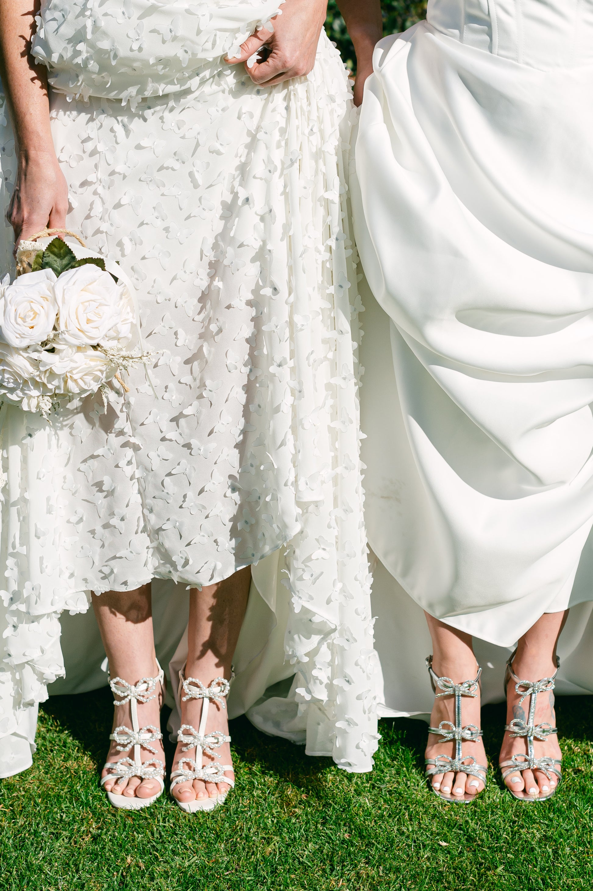 Pearl and rhinestone bows on a 4.25" block heel in metallic silver and pearlescent white worn by two women wearing white dresses