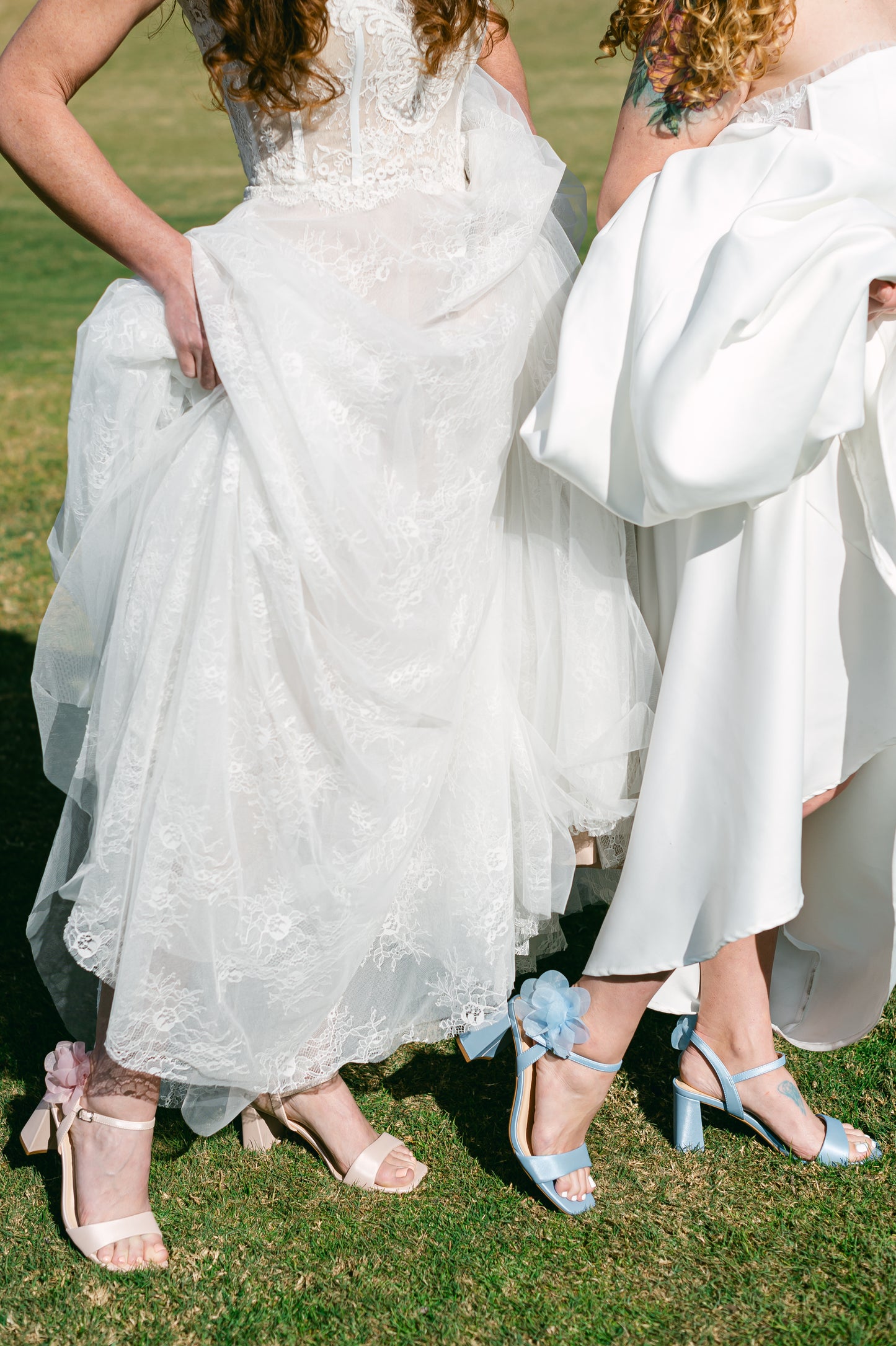 Flared 3" block heels in blue and pink with slim ankle strap and flower detail worn by two women in white dresses