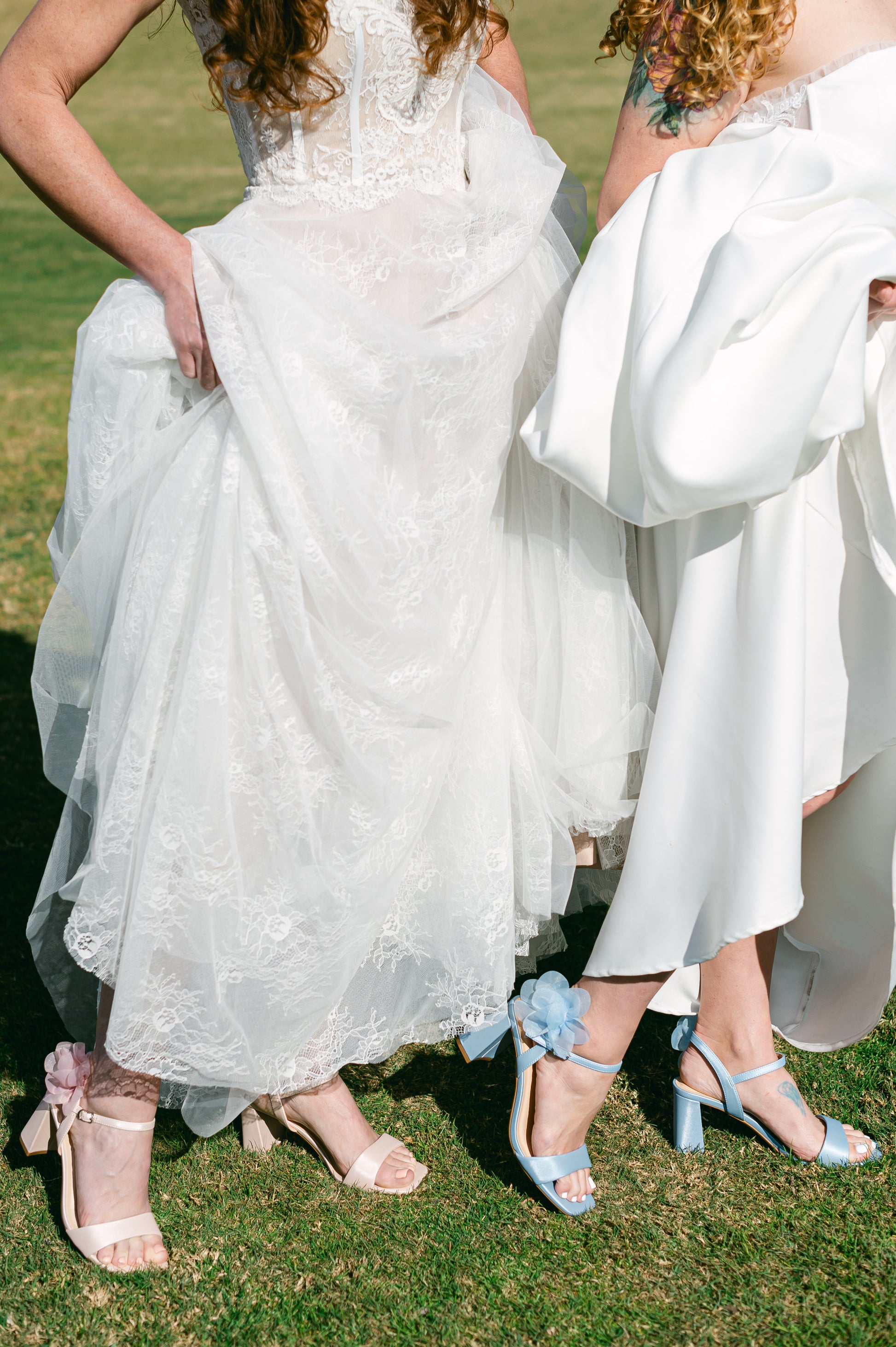 Flared 3" block heels in blue and pink with slim ankle strap and flower detail worn by two women in white dresses
