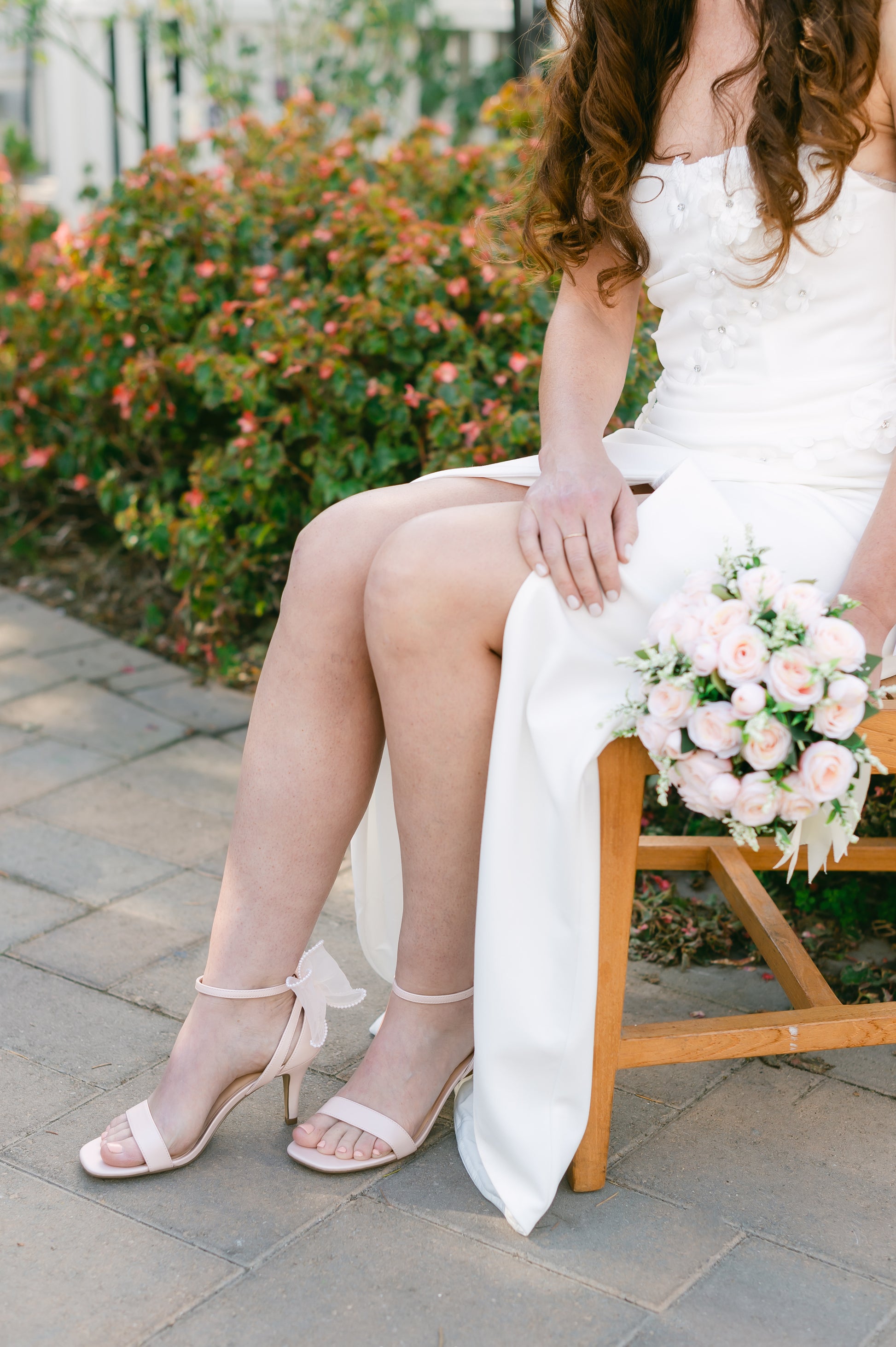 Simple single-band 3" stiletto heel in white with a beaded bow on the back worn by a woman in a white dress