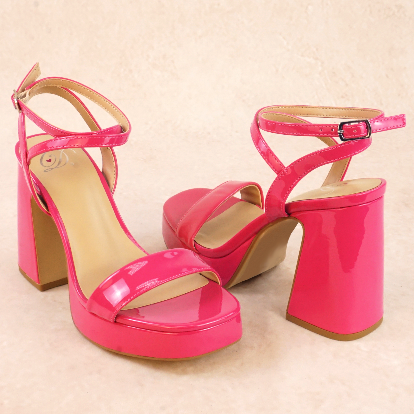 A pair of pink patent material platform high heels with adjustable ankle strap