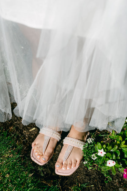 T-strap pink sandal with adjustable slingback and pearl and rhinestone accents being worn