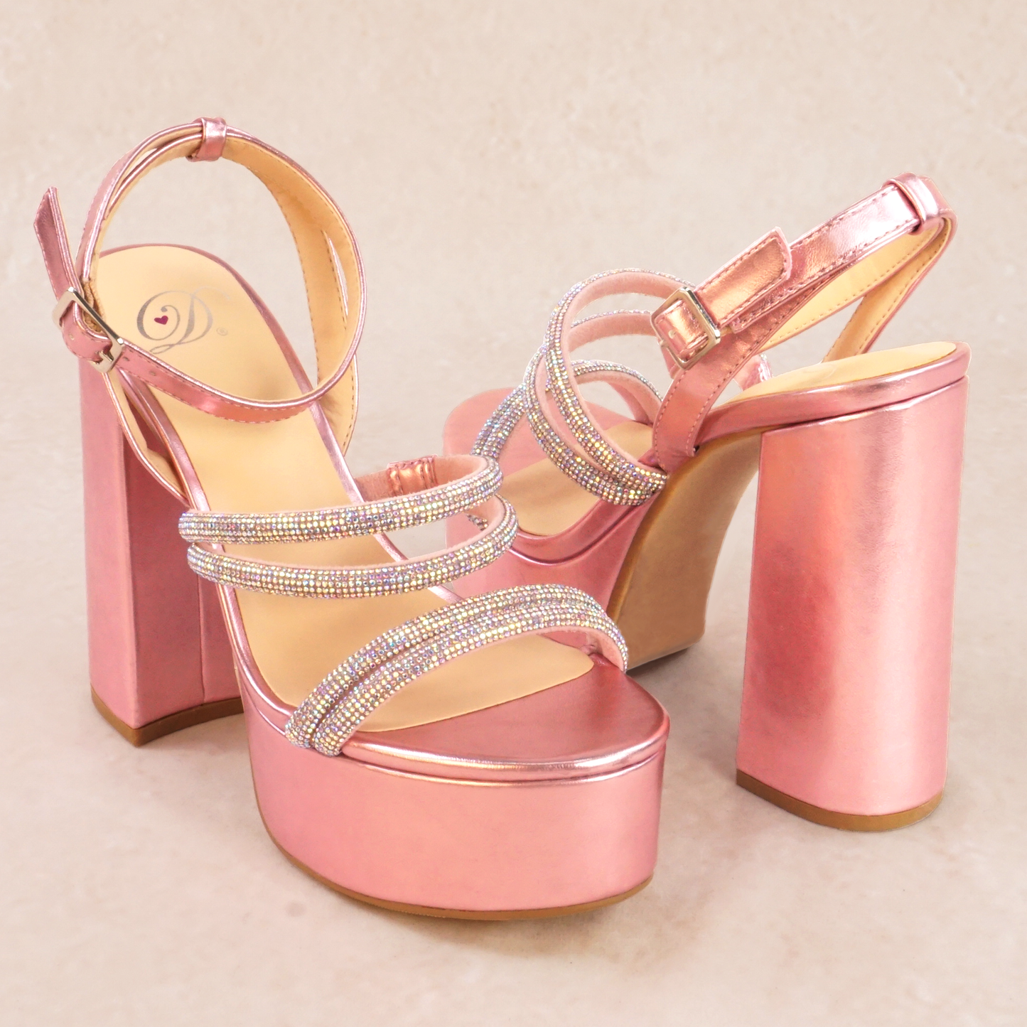 A pair of pink metallic platform heels with rhinestone straps and adjustable ankle strap