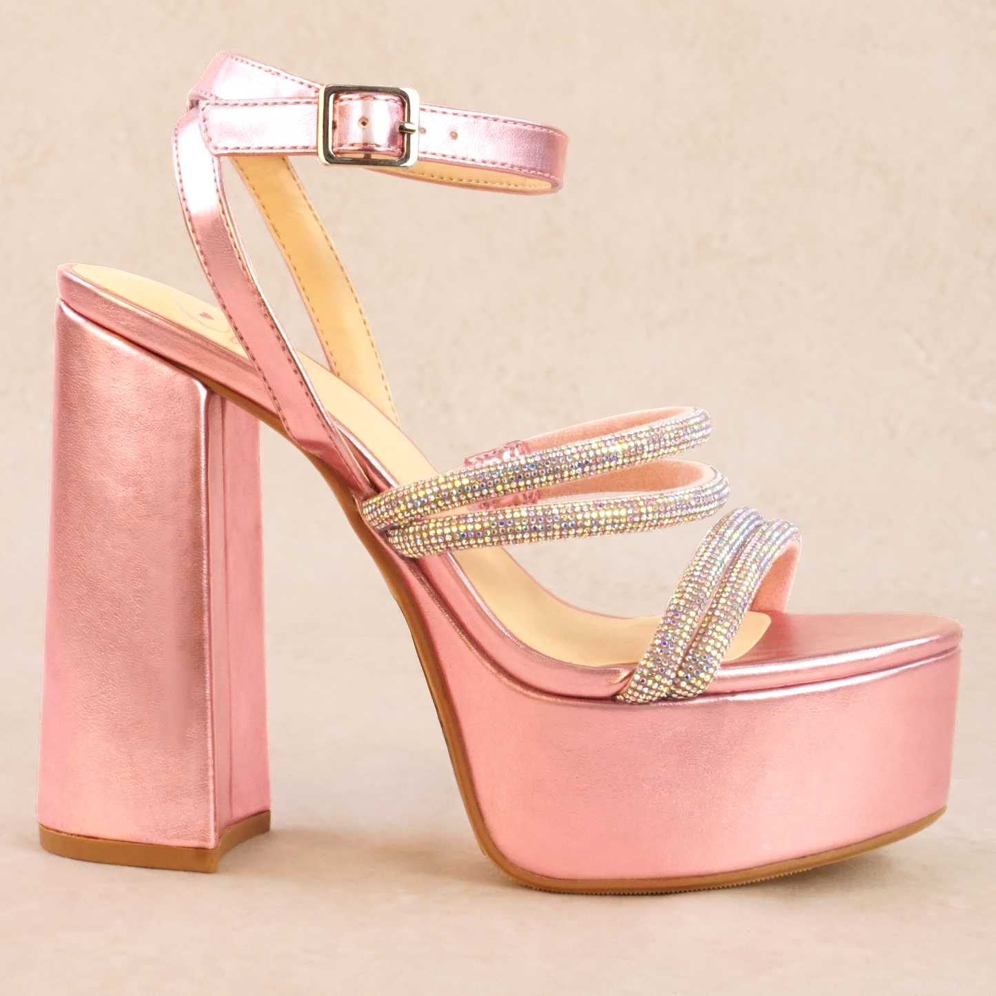 A pink metallic platform heel with rhinestone straps and adjustable ankle strap