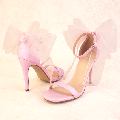 A pair of pink satin stiletto heels with mesh bow and adjustable ankle strap