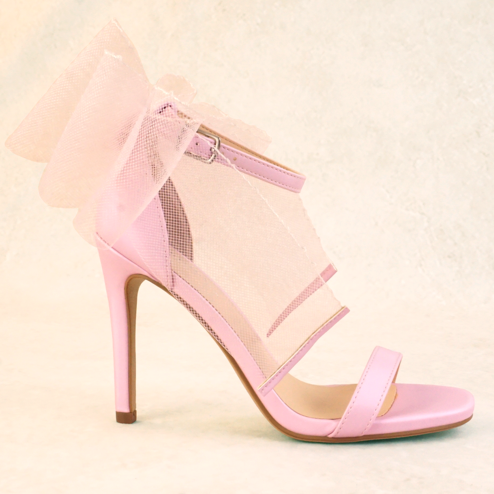 A pair of pink satin stiletto heels with mesh bow and adjustable ankle strap