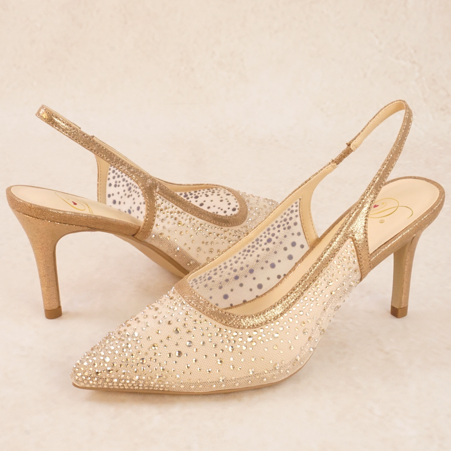 A pair of rose gold mesh rhinestone studded pump heels with elastic slingback strap