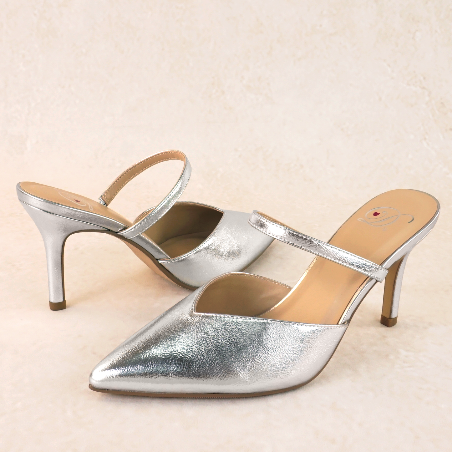 A silver closed-toe stiletto heel shoe in a shiny metallic material and an elasticized strap across the foot