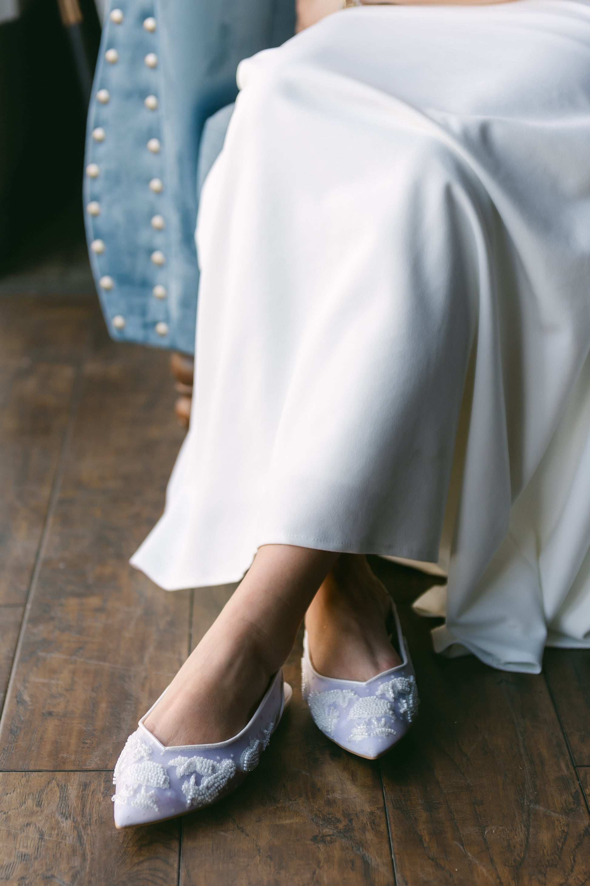 Pointed-toe slingback mesh white flat with beading worn by a woman in a white dress