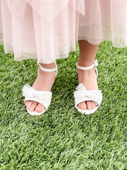 1.75" block heel white sandal with tulle glitter bow detail being worn