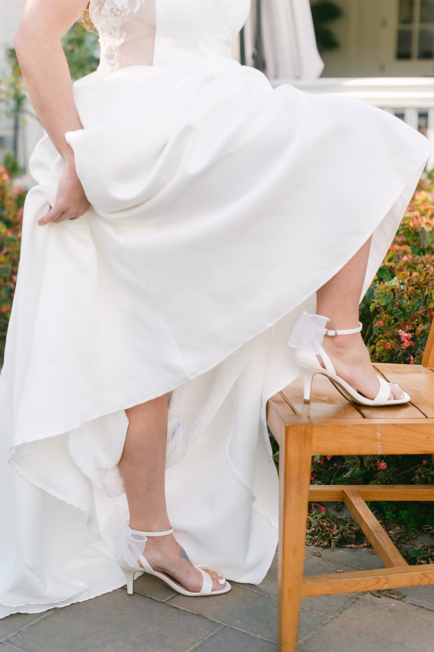 Simple single-band 3" stiletto heel in white with a beaded bow on the back worn by a woman in a white dress