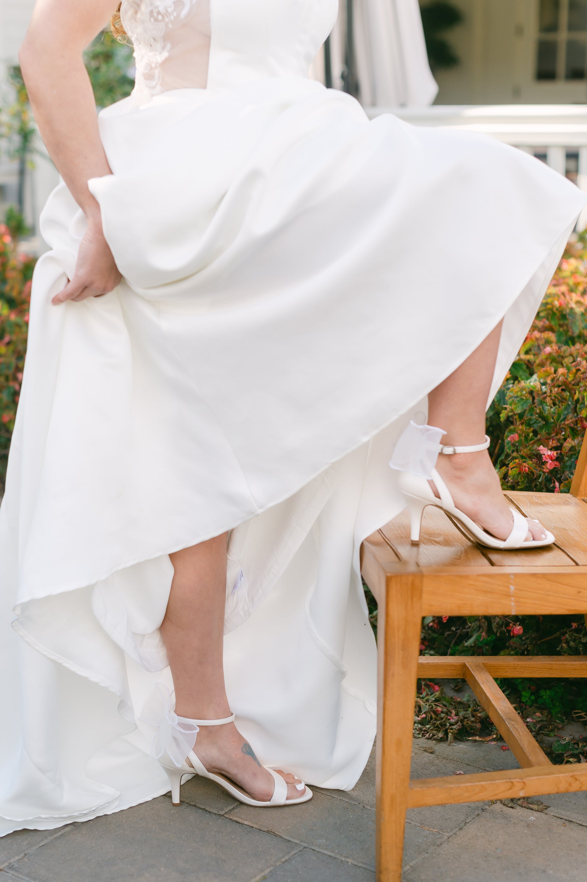 Simple single-band 3" stiletto heel in white with a beaded bow on the back worn by a woman in a white dress