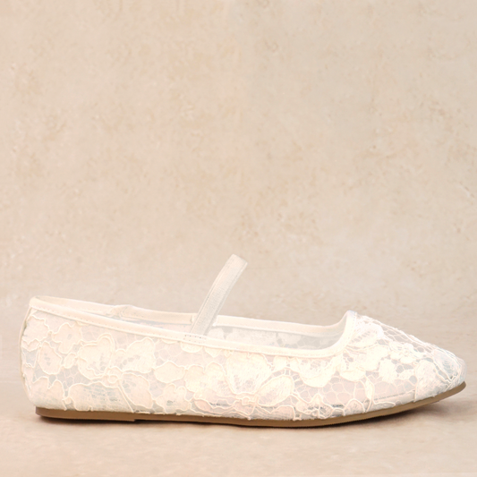 A white flat shoe with floral lace pattern allover and Mary Jane style elastic strap