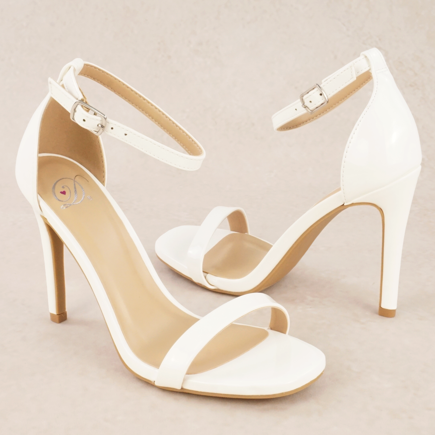 A pair of white patent material stiletto heels with adjustable ankle straps