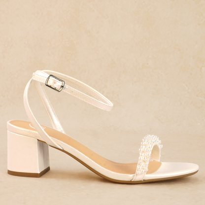 A white pearlescent sandal with an adjustable ankle strap and pearl detailing on the band