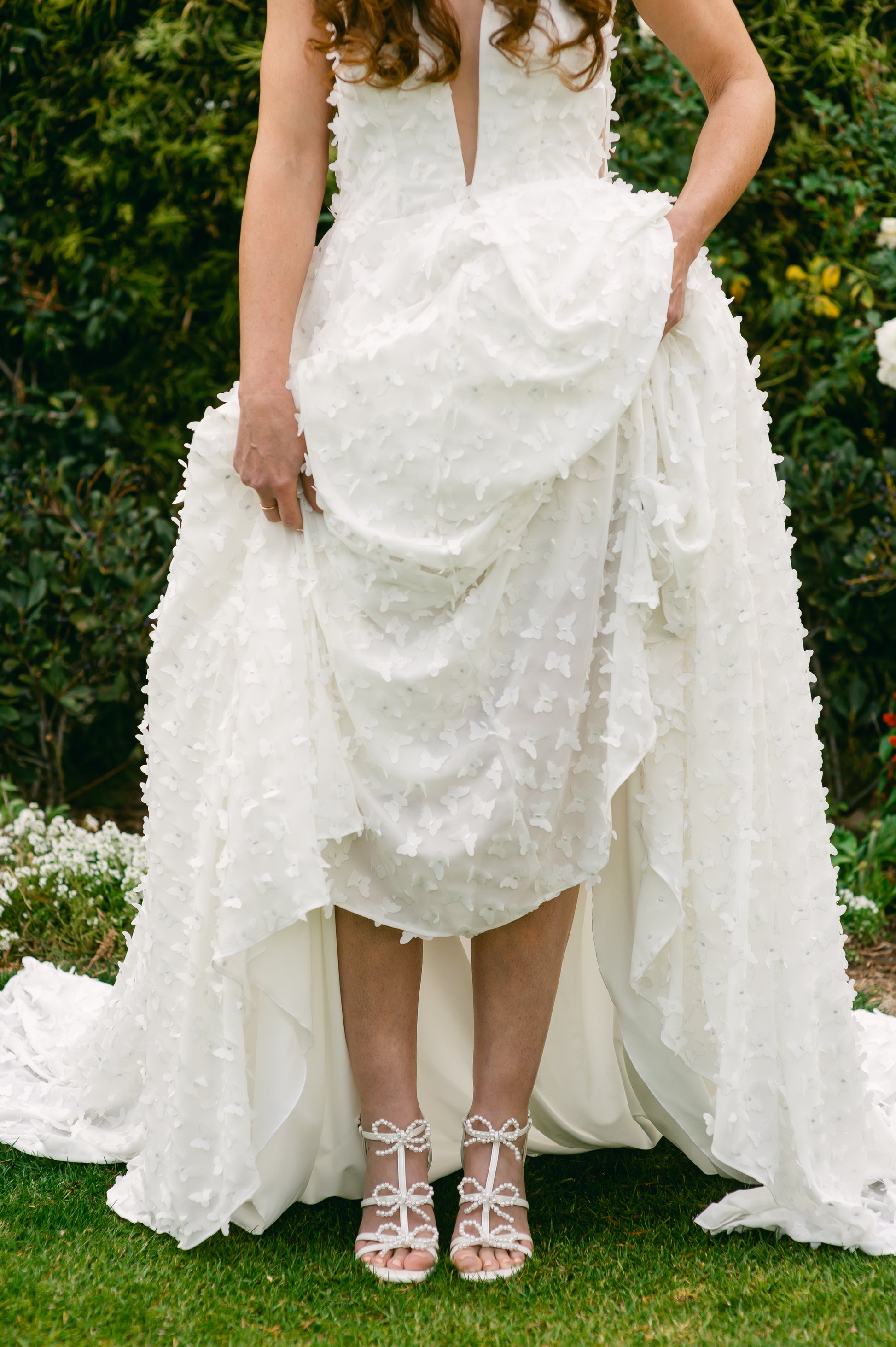 Pearl and rhinestone bows adorn a 4.25" block heel in pearlescent white worn by a woman in a white dress