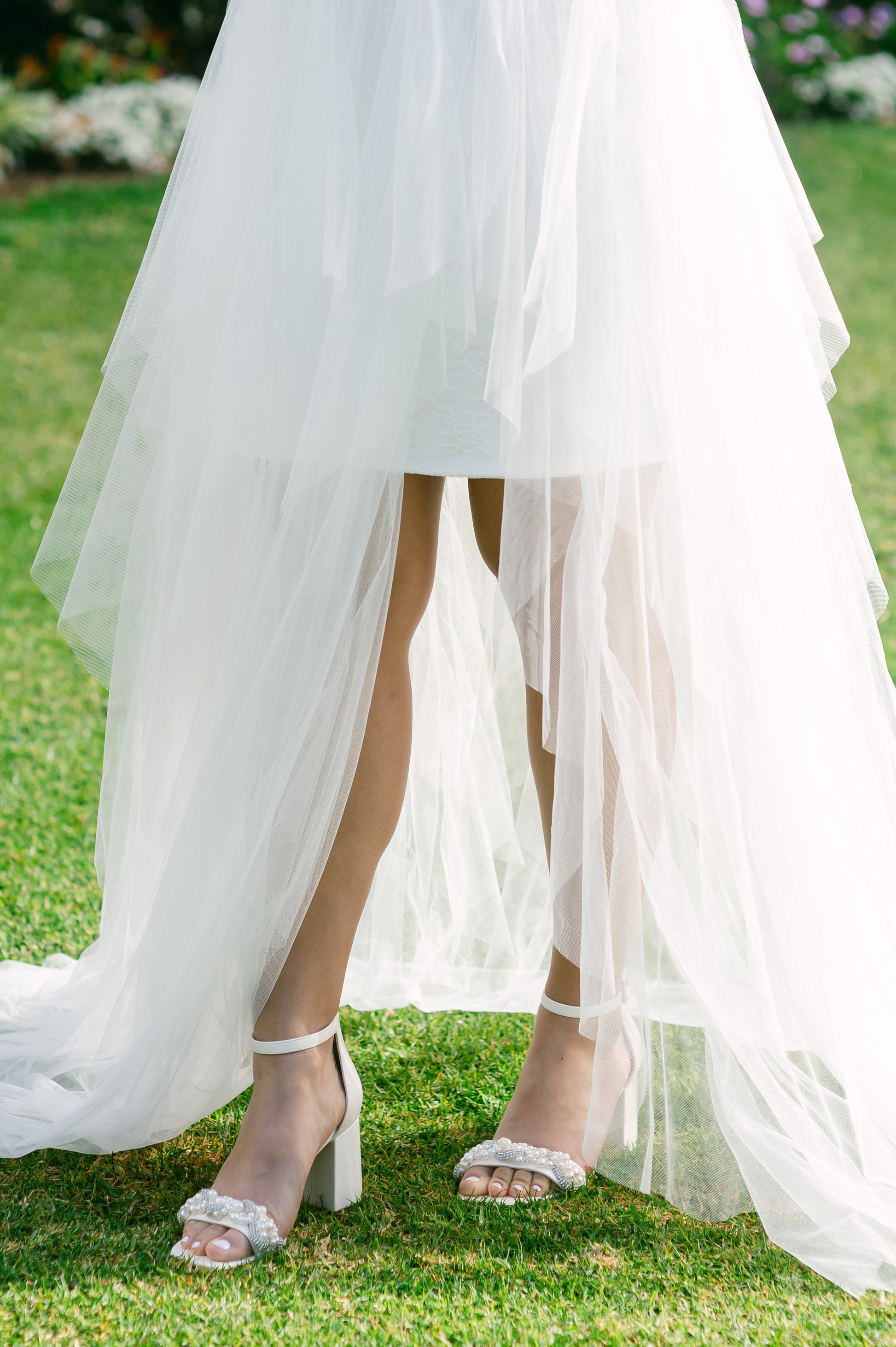 Pearls and rhinestones intertwined on a wide fit single-band 3.25" ankle strap block heel worn by a woman in a white dress
